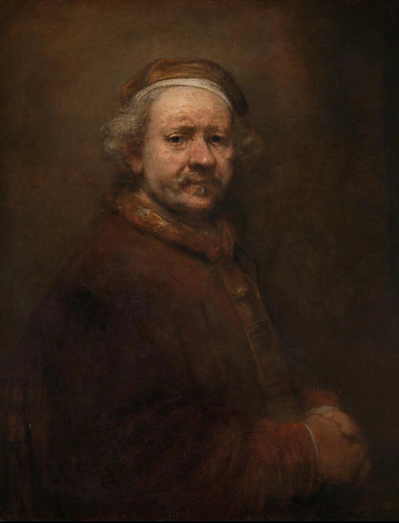 The image is a portrait of a man with a serious expression, wearing a hat and a long coat.