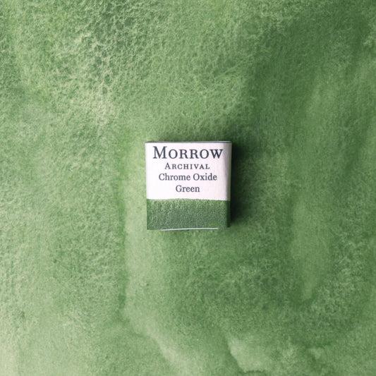 Handmade Chrome Green natural watercolor paint half pan shown on a textured watercolor painting. Crafted from pure single-pigment chromium oxide, this deep, opaque green offers strong coverage, smooth handling, and excellent lightfastness‚Äîperfect for botanical art, landscape painting, and historical illustration. A durable eco-friendly gift for watercolor artists and collectors seeking small-batch, archival-quality, all-natural handmade pigments rooted in traditional colormaking.