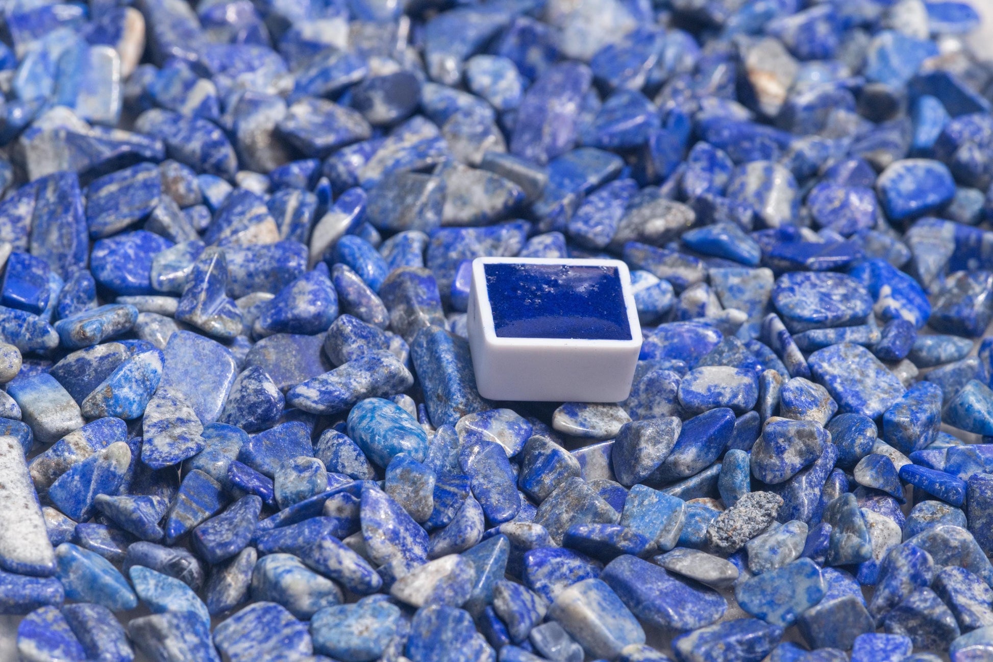 Lapis Blue watercolor half pan resting on a vibrant, raw lapis lazuli stone‚Äîthe legendary source of this brilliant ultramarine pigment. Handcrafted from genuine Afghan lapis, this artist-grade watercolor captures the intense, luminous blue prized by Renaissance masters. Ideal for fine art, iconography, and historical palettes. For Lapis Blue watercolor, natural ultramarine pigment, lapis lazuli paint, and premium handmade art supplies.