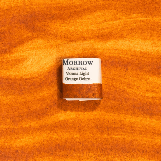 Handmade Verona Orange Ochre natural watercolor paint half pan displayed on a textured watercolor painting. Crafted from pure single-pigment natural earth sourced near Verona, Italy, this warm, earthy orange offers soft granulation and excellent transparency, perfect for botanical illustration, landscape painting, and historical fine art. A beautiful eco-friendly gift for watercolor artists and collectors seeking small-batch, archival-quality, all-natural handmade pigments.