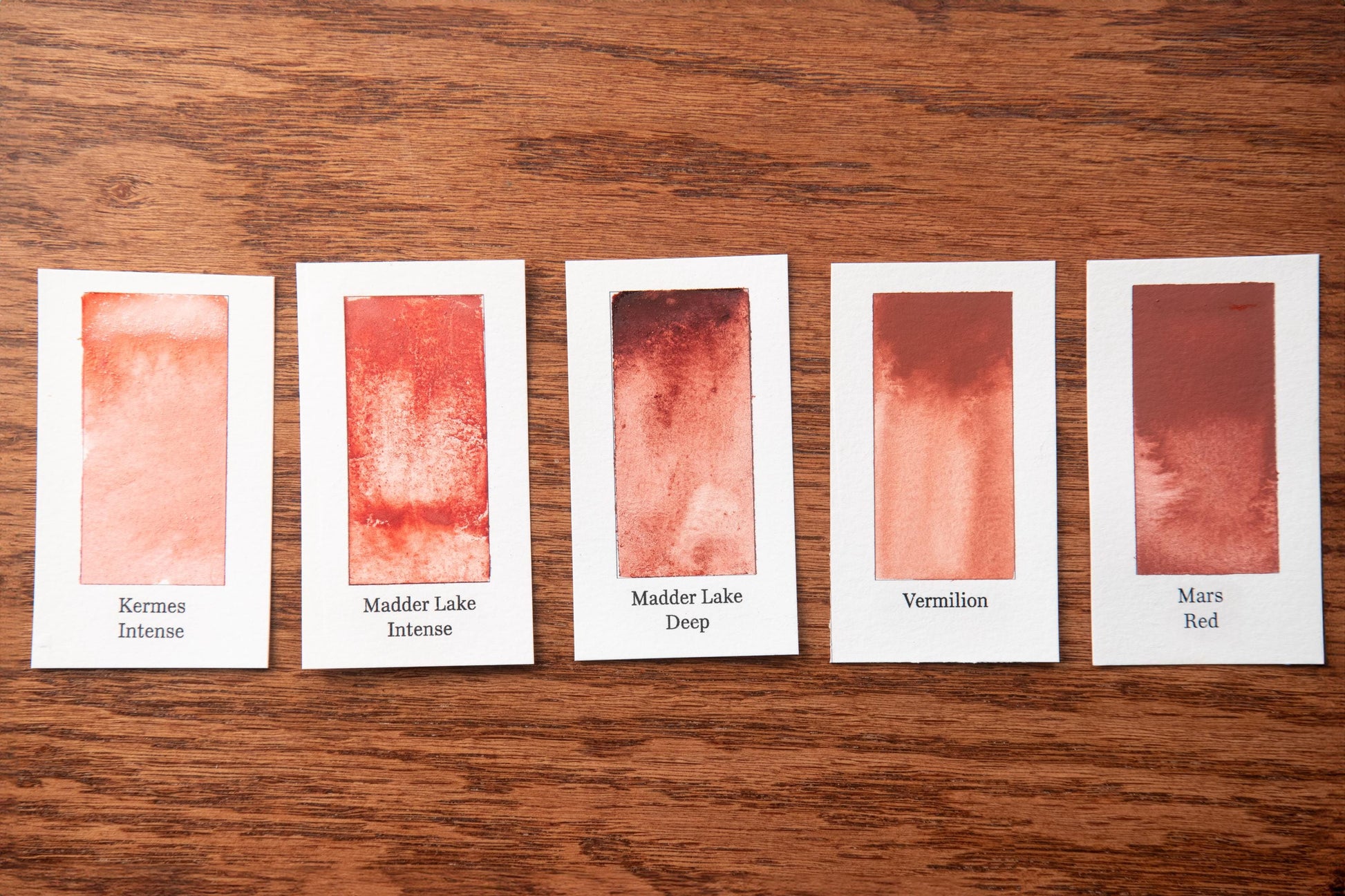 five different shades of red paint, each with a label indicating the name of the color.