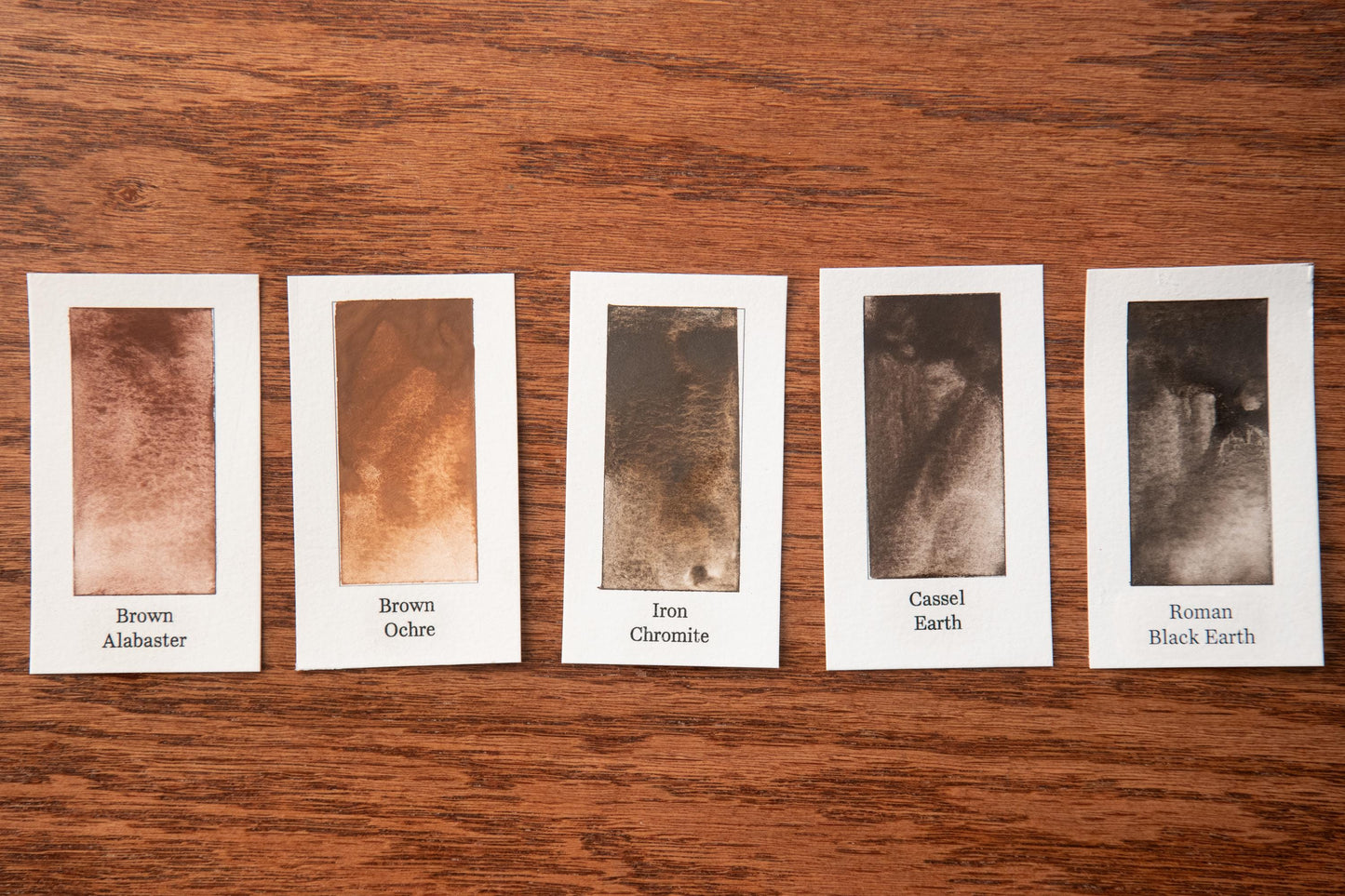 five different shades of brown, each corresponding to a different type of soil, arranged on a wooden surface.