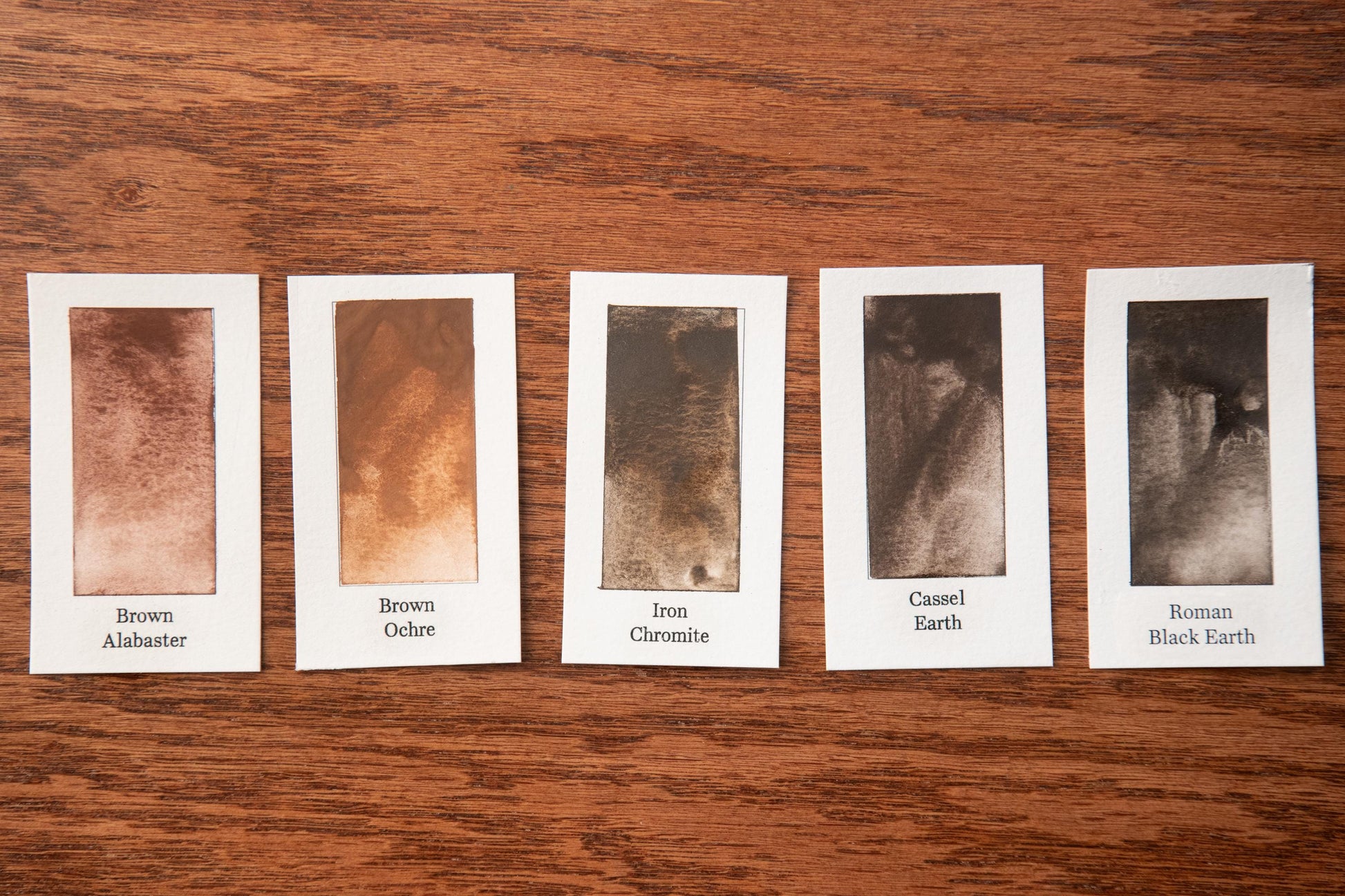 five different shades of brown, each corresponding to a different type of soil, arranged on a wooden surface.