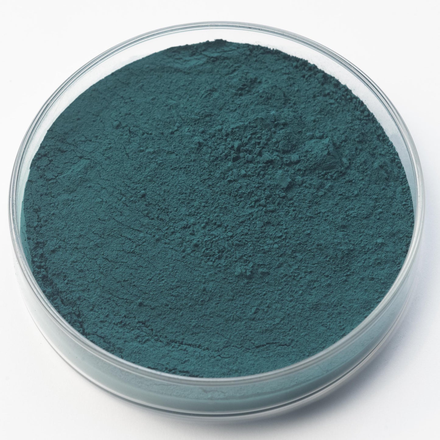 A clear petri dish displays a fine, dark teal green powder of Cobalt Blue Deep Pigment on a white background.