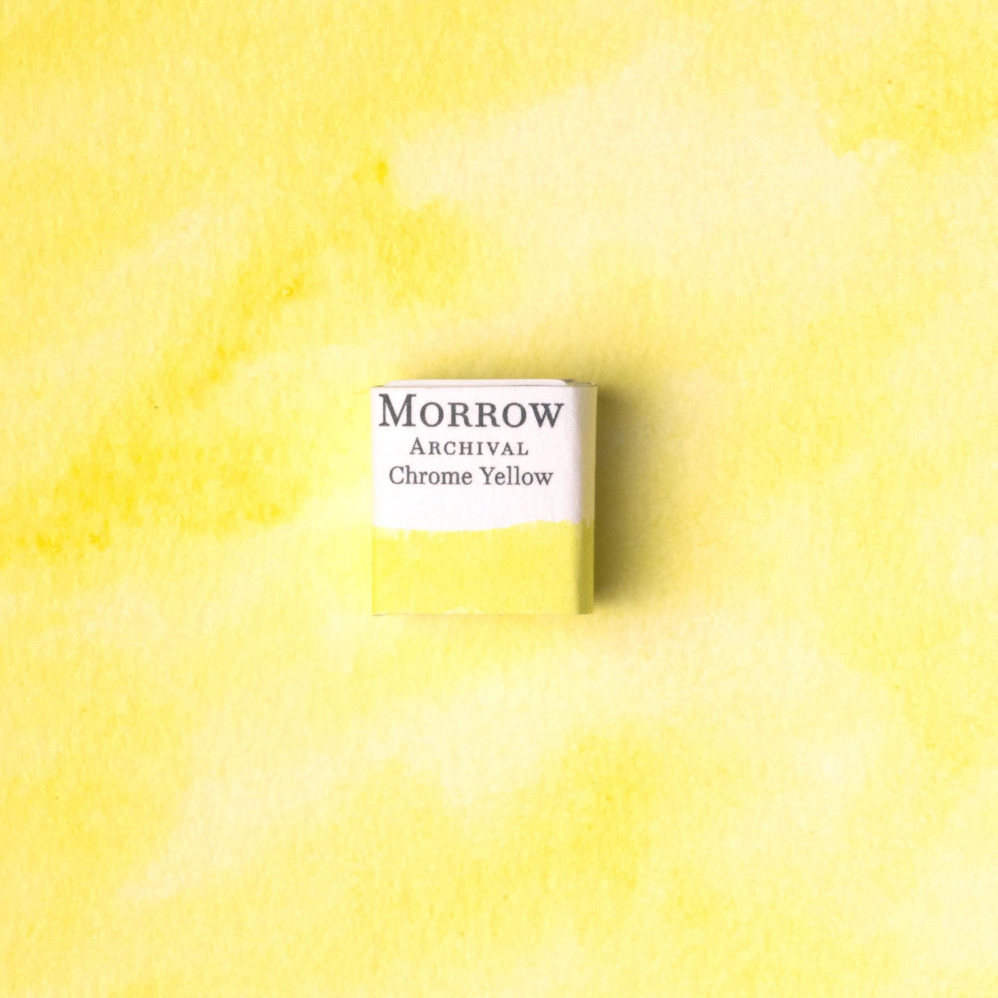 Handmade Chrome Zinc Yellow natural watercolor paint half pan resting on a textured watercolor painting. Made from pure single-pigment zinc chromate, this bright, opaque yellow offers excellent coverage, vibrant tone, and historic authenticity‚Äîideal for botanical illustration, vintage palette recreations, and fine art painting. A striking eco-friendly gift for watercolor artists and collectors seeking small-batch, archival-quality, all-natural handmade pigments with industrial-era roots.