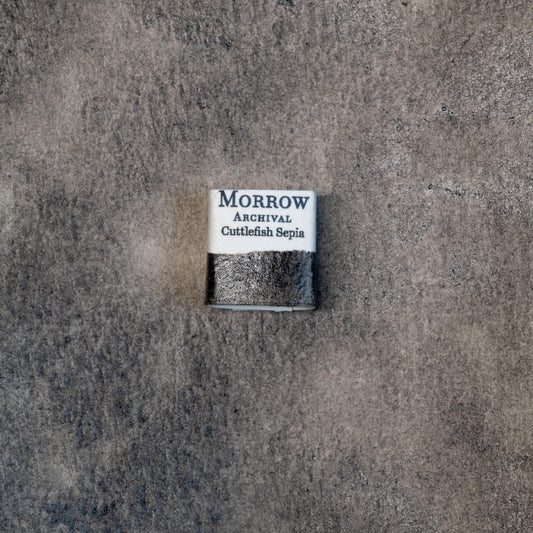 Close-up image of a half pan of Cuttlefish Sepia handmade watercolor paint, featuring a rich, warm brown-black hue with a soft matte finish and gentle transparency. The pan is set on a neutral background, highlighting the pigment‚Äôs marine animal origin and historical craftsmanship. Ideal for artists seeking a true Old Master-style sepia for monochrome and tonal work.