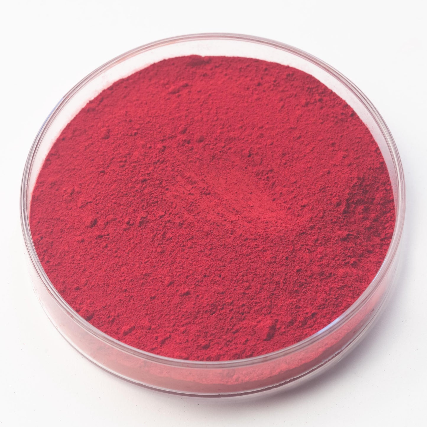 A round glass container filled with a red powder-like substance.