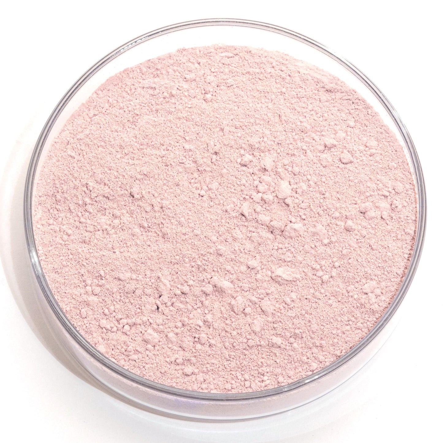 A clear glass bowl filled with a pink-colored powder or substance, sitting on a white surface.