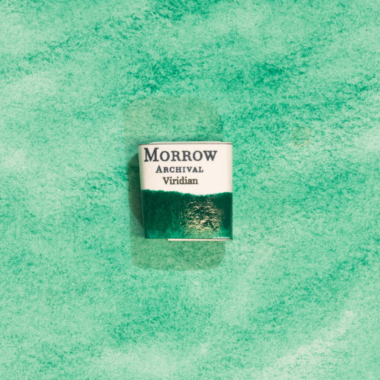 Handmade Viridian Green natural watercolor paint half pan resting on a textured watercolor painting. Crafted from pure single-pigment hydrated chromium oxide, this cool, vibrant green offers excellent transparency and smooth granulation, perfect for botanical illustration, landscape painting, and fine art. An ideal eco-friendly gift for watercolor artists and collectors seeking small-batch, archival-quality, all-natural handmade pigments rooted in historical tradition.