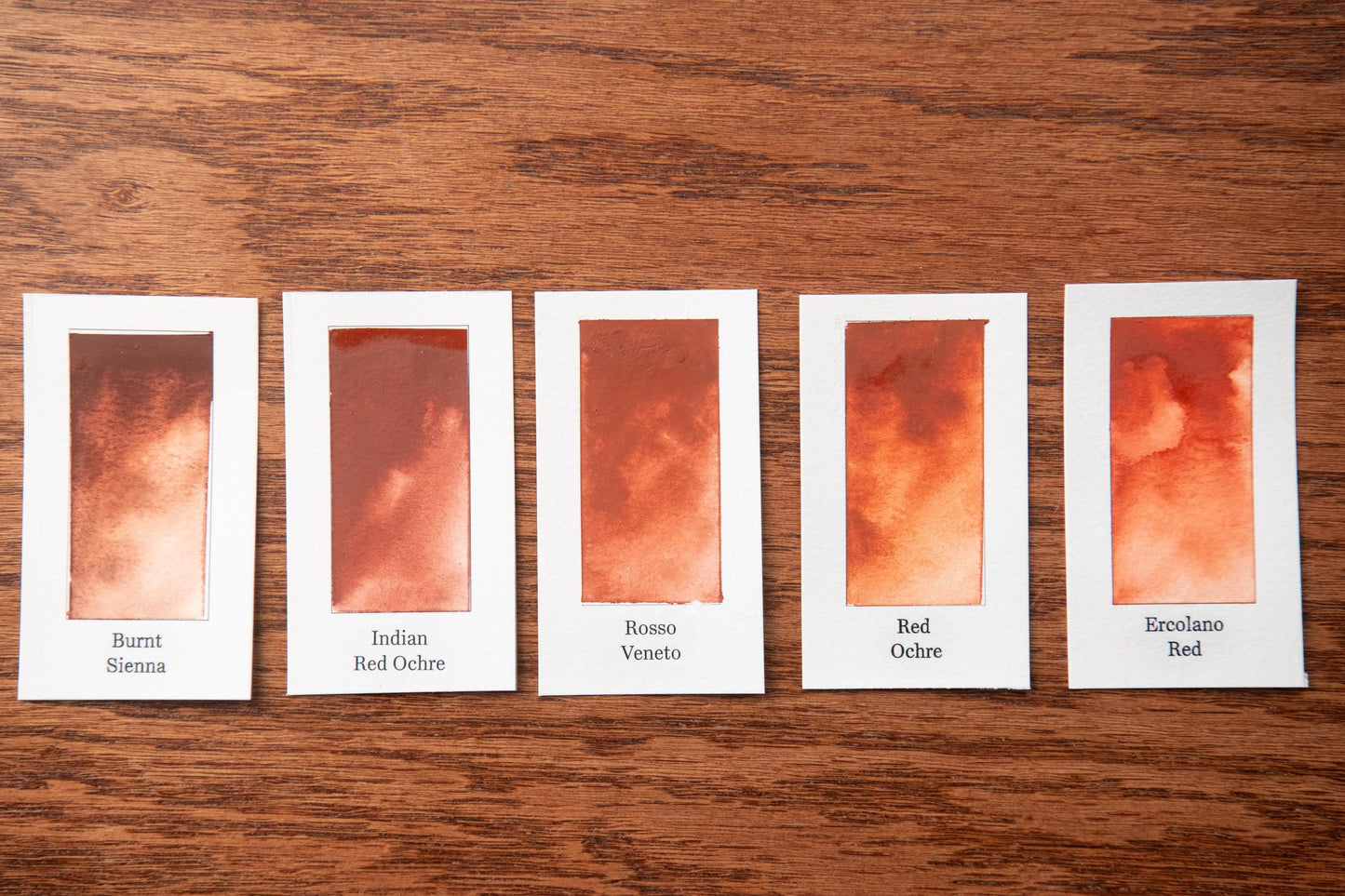 five different shades of red paint, each with a label indicating the name of the color.