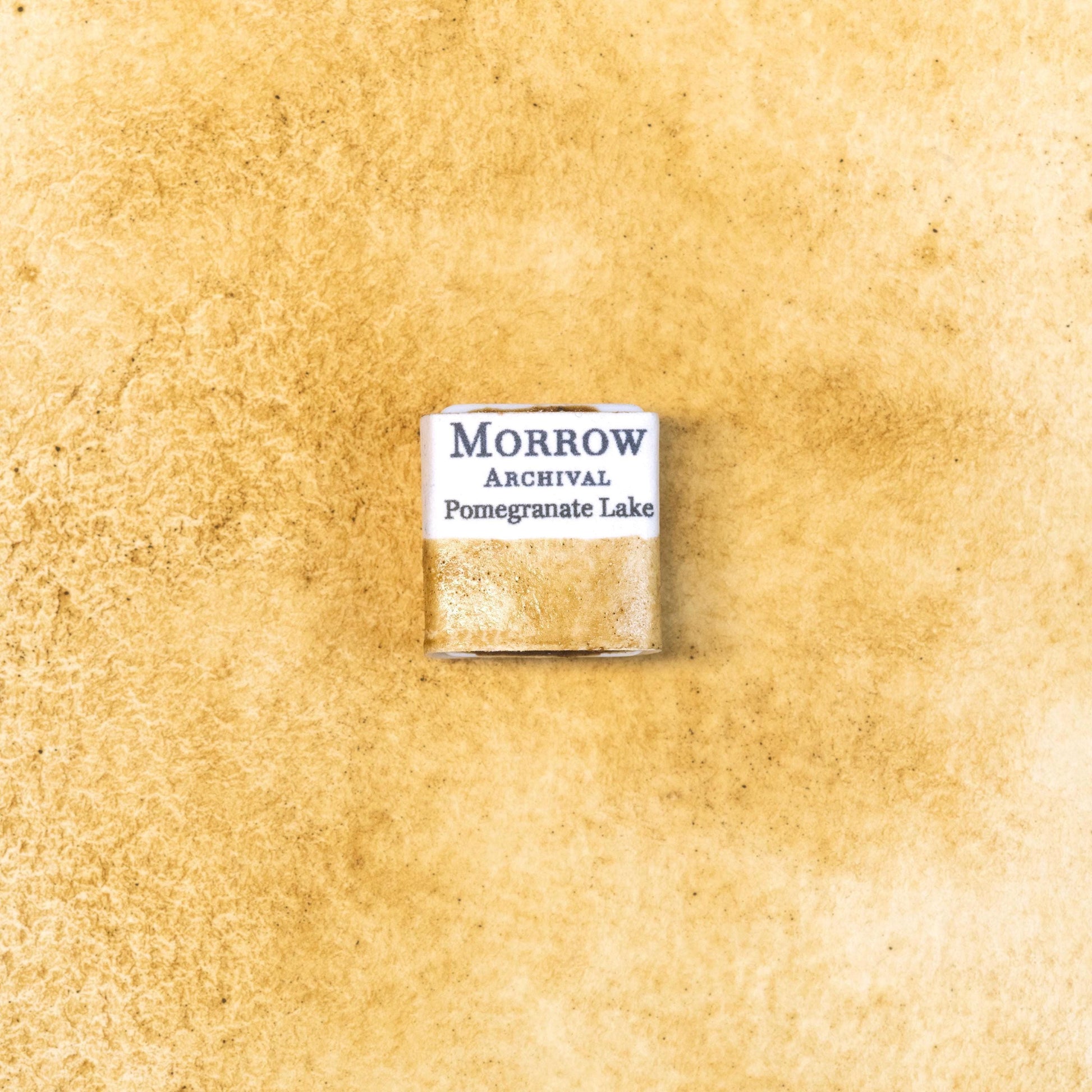 Close-up image of a half pan of Pomegranate Yellow Lake handmade watercolor paint, showing a warm, golden-yellow hue with soft transparency and smooth surface. The pan is set on a neutral background, highlighting the pigment‚Äôs botanical origin and traditional craftsmanship. Ideal for artists seeking a natural, earthy yellow with historical and cultural depth.