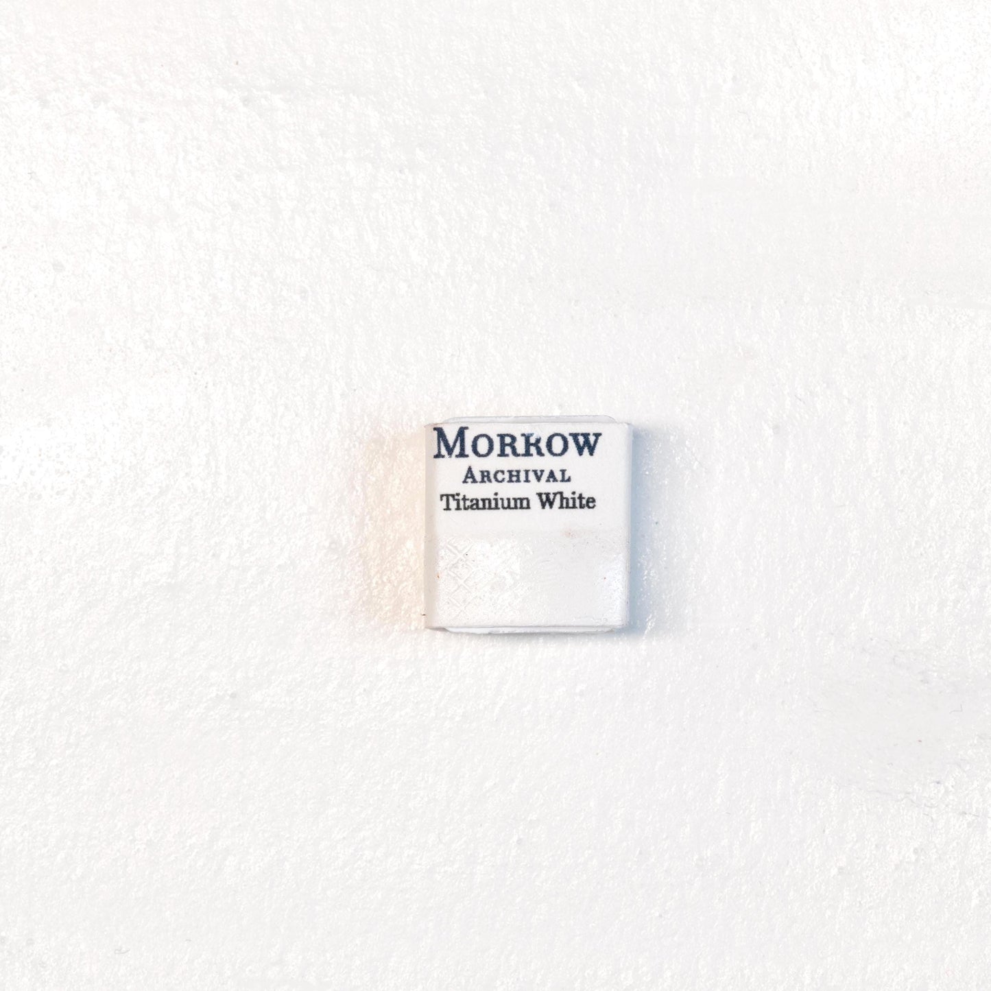 Close-up image of a half pan of Titanium White handmade watercolor paint, showing a bright, pure white with a smooth, opaque matte surface. The pan rests on a neutral background, highlighting its mineral purity and artisanal craftsmanship. Ideal for artists seeking a clean, permanent white for highlights, tints, and opaque effects.