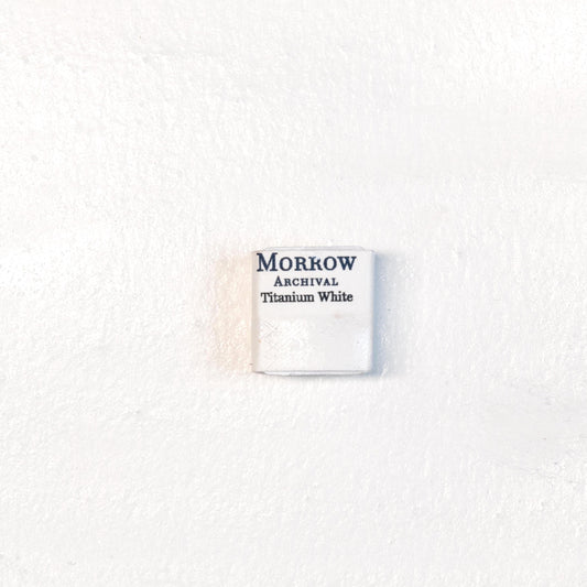 Close-up image of a half pan of Titanium White handmade watercolor paint, showing a bright, pure white with a smooth, opaque matte surface. The pan rests on a neutral background, highlighting its mineral purity and artisanal craftsmanship. Ideal for artists seeking a clean, permanent white for highlights, tints, and opaque effects.