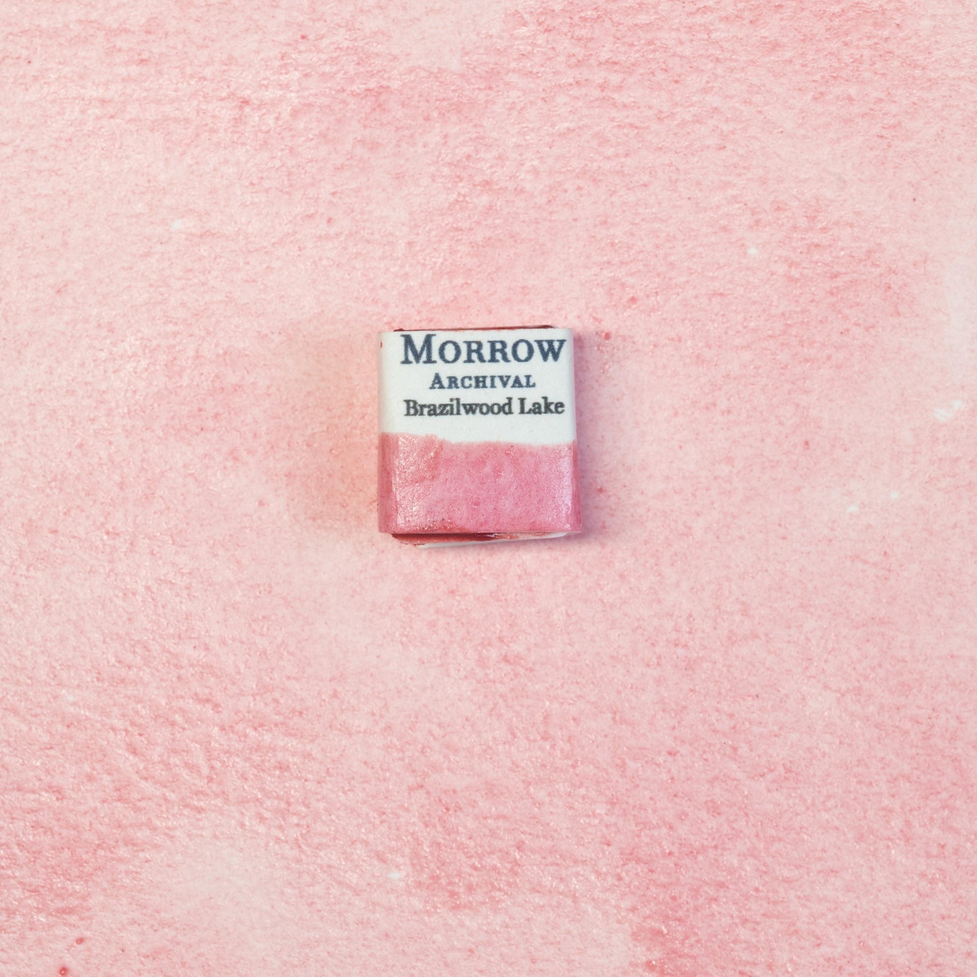 Close-up image of a half pan of Brazilwood Lake Pink handmade watercolor paint, showing a warm, ros√©-pink hue with a soft, translucent finish. The pan sits on a neutral background, highlighting its botanical origin and traditional craftsmanship. Ideal for artists seeking a natural, historical pink with elegance and floral charm.