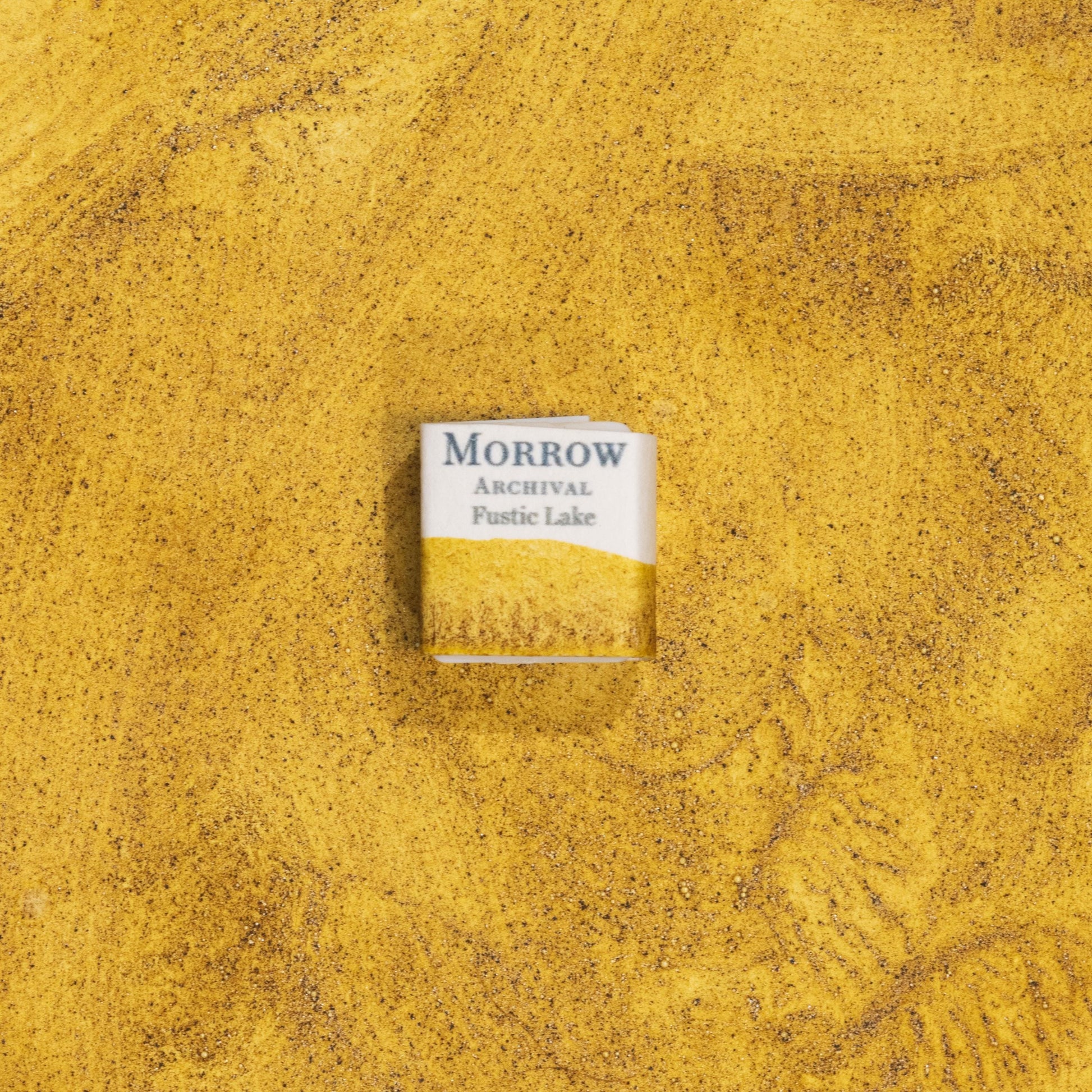 Handmade Fustic Lake Deep Yellow natural watercolor paint half pan shown on a textured watercolor painting. Crafted from pure single-pigment fustic wood extract, this rich golden yellow offers warm transparency and soft granulation, perfect for botanical painting, historical illustration, and naturalist art. A beautiful eco-friendly gift for watercolor artists and collectors seeking small-batch, archival-quality, all-natural handmade pigments with a deep historical legacy.