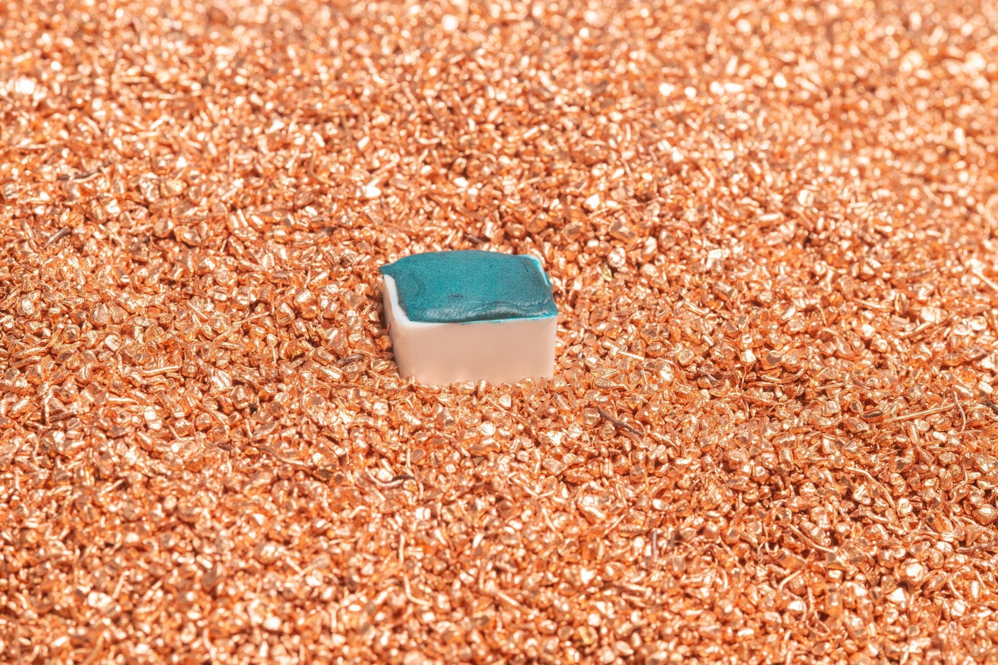 Verdigris fine watercolor half pan resting on raw copper metal, showcasing the authentic source of this vibrant, historic green pigment. Handcrafted from copper salts using traditional methods, this artist-grade watercolor offers luminous bluish-green tones prized since antiquity. Perfect for classical painting, historical palettes, and natural pigment collectors. Optimized for handmade verdigris watercolor, copper-based pigments, and eco-friendly art supplies.