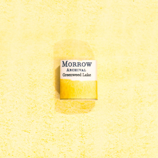 Handmade Greenweed Lake Yellow natural watercolor paint half pan shown on a textured watercolor painting. Crafted from pure single-pigment greenweed plant extract, this bright, natural yellow offers beautiful transparency and gentle granulation, ideal for botanical illustration, historical painting, and fine art. A perfect eco-friendly gift for watercolor artists, nature enthusiasts, and collectors seeking small-batch, archival-quality, all-natural handmade pigments.