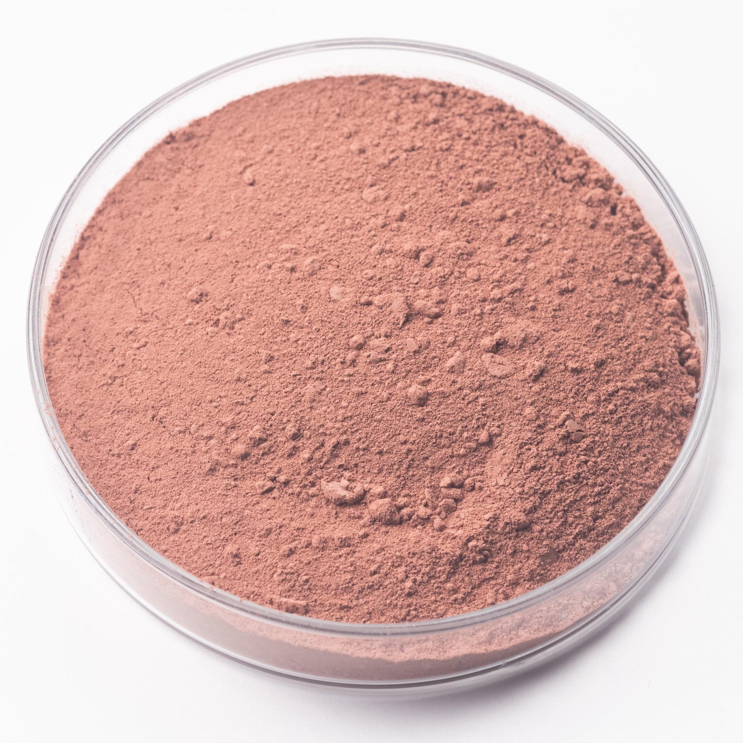 A clear petri dish holds Sorghum Lake Pigment, a handmade, plant-based reddish-brown powder with a smooth texture and some small clumps, displayed on a white background.