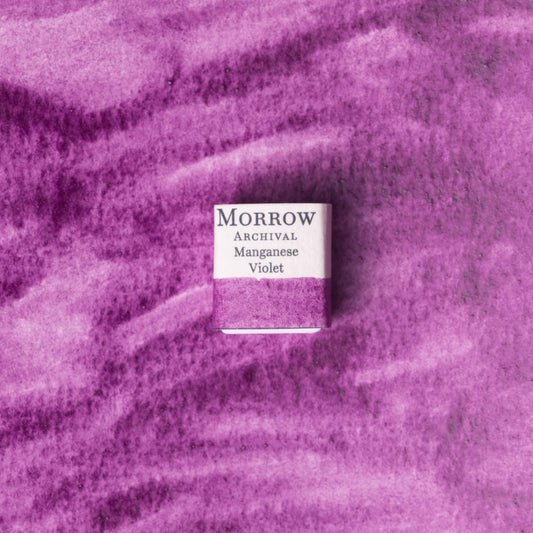 Handmade Manganese Violet natural watercolor paint half pan displayed on a textured watercolor painting. Made from pure single-pigment manganese phosphate, this vibrant yet soft violet offers smooth granulation and strong lightfastness‚Äîideal for floral painting, portraits, and fine art illustration. A striking eco-friendly gift for watercolor artists and collectors seeking small-batch, archival-quality, all-natural handmade pigments with a legacy in classical color palettes.