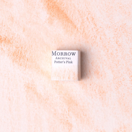 Handmade Potter‚Äôs Pink natural watercolor paint half pan resting on a textured watercolor painting. Crafted from pure single-pigment manganese-derived pink, this soft, muted rose hue offers gentle granulation and delicate transparency‚Äîperfect for botanical art, portrait work, and historical illustration. A subtle, eco-friendly gift for watercolor artists and collectors seeking small-batch, archival-quality, all-natural handmade pigments with a refined, classical aesthetic.