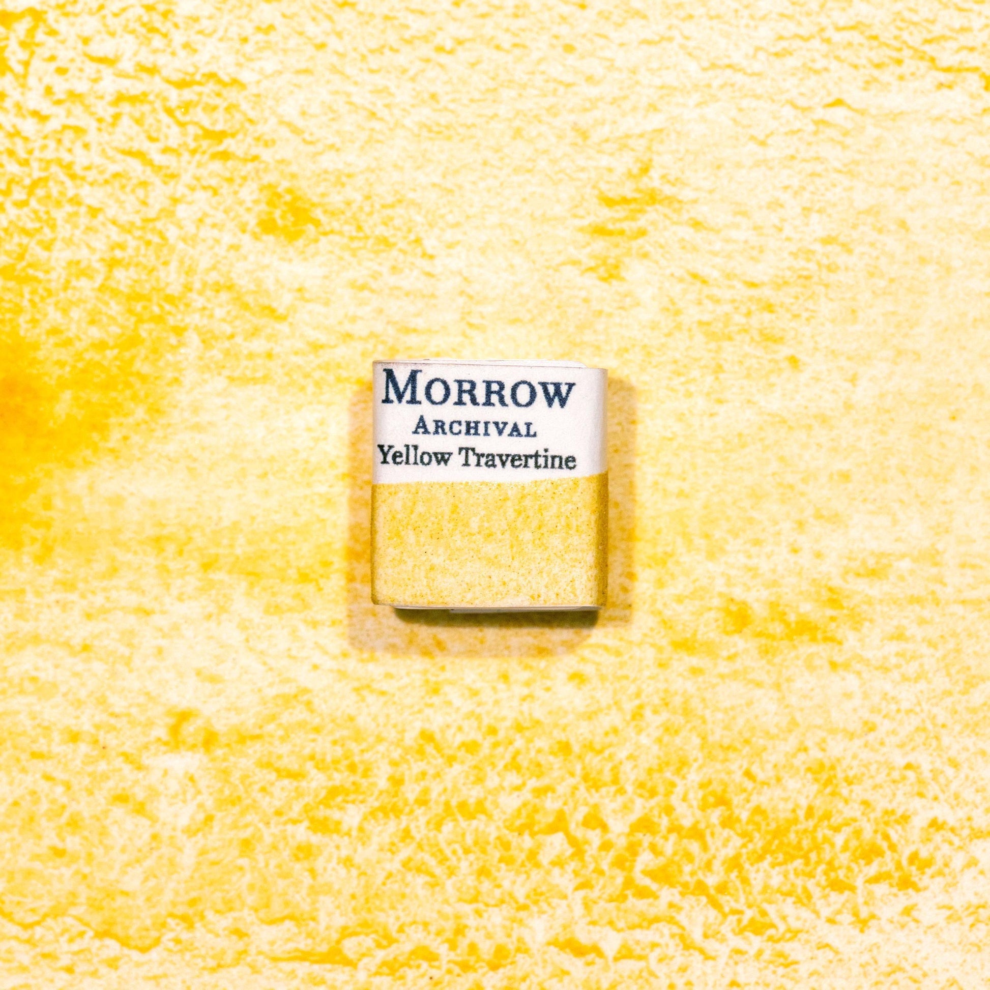 Watercolor painting with a handmade archival watercolor pan with elegant and vibrant label in watercolor paper in Natural Stone Yellow Travertine, a soft, sun-washed yellow pigment ground from natural travertine limestone rich in iron oxide, echoing the tones of ancient Roman architecture and frescoes. Handcrafted with honey and gum arabic. Semi-opaque and lightfast, ideal for classical palettes, architectural sketches, and warm earth-toned compositions.