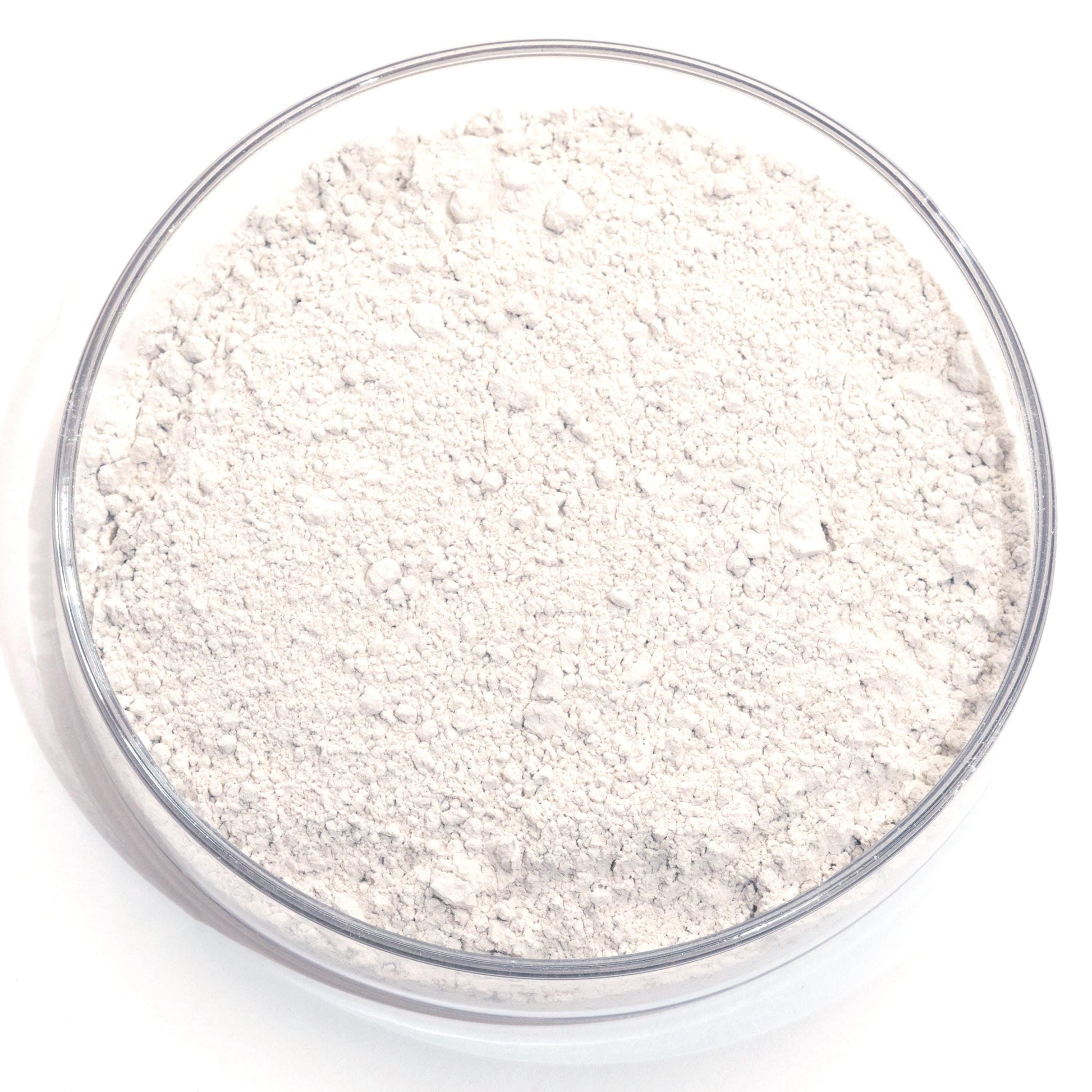 A glass bowl filled with a white powdery substance, possibly flour or cornstarch, sits on a white background.
