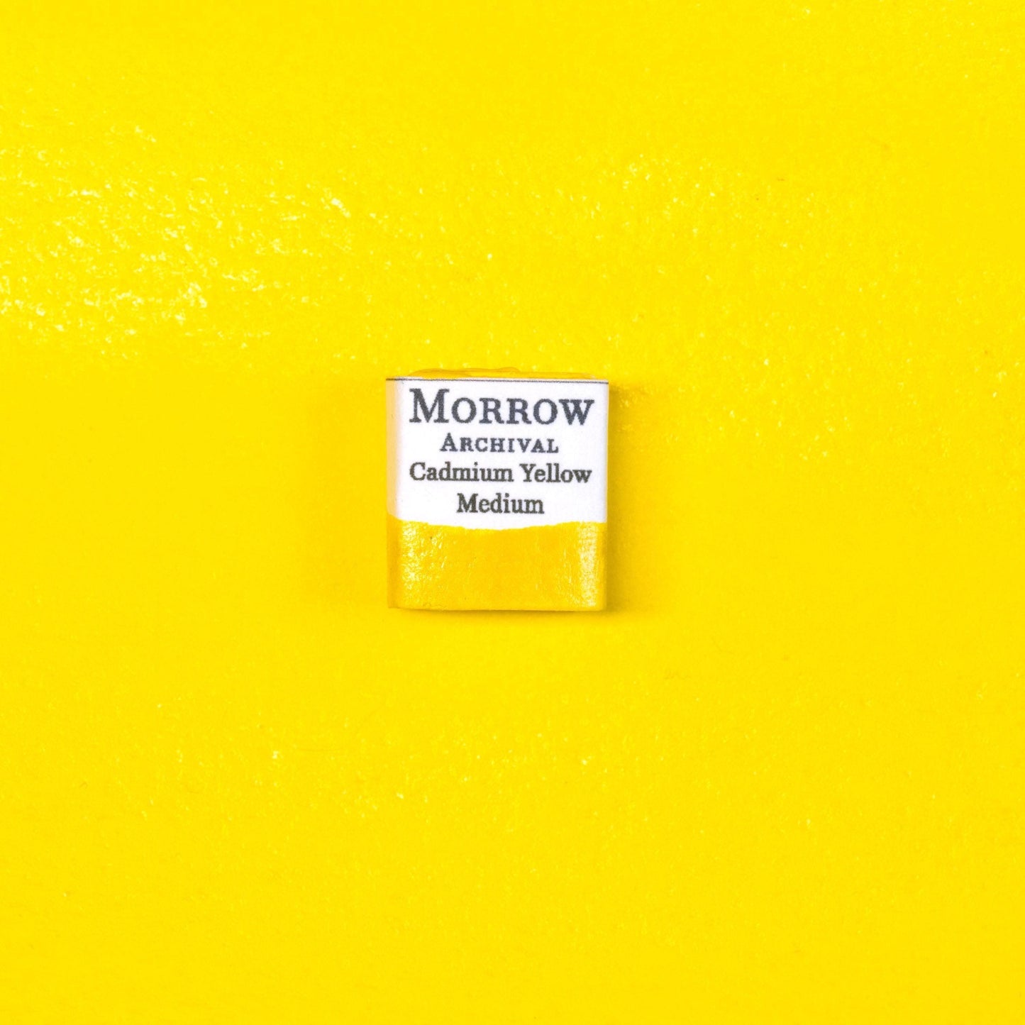 Close-up image of a half pan of Cadmium Yellow Medium handmade watercolor paint, featuring a vivid, golden-yellow hue with a smooth, opaque surface. The pan rests on a neutral background, emphasizing the pigment‚Äôs bold color and artisanal craftsmanship. Ideal for artists seeking a warm, permanent yellow with rich historical and professional pedigree.