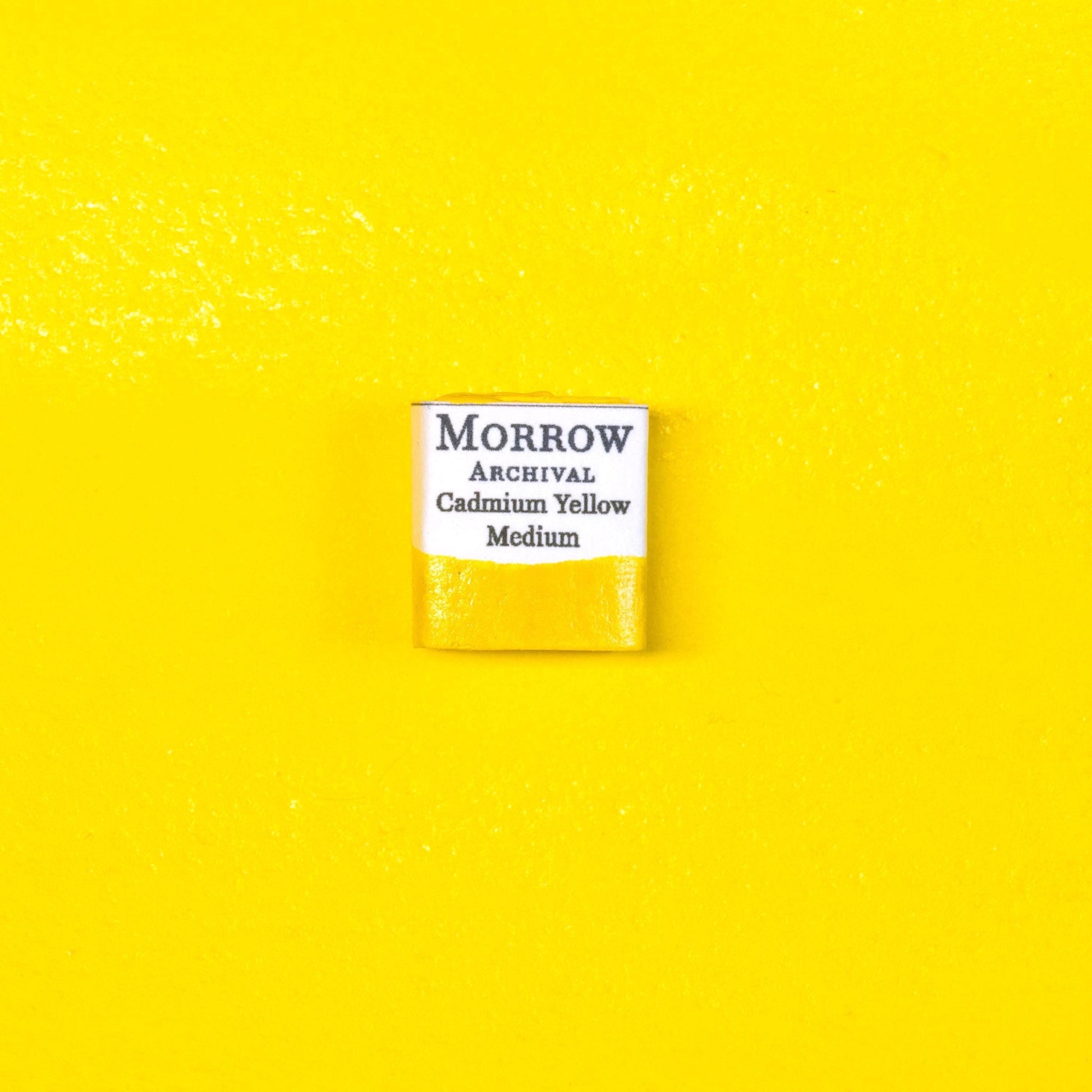 Close-up image of a half pan of Cadmium Yellow Medium handmade watercolor paint, featuring a vivid, golden-yellow hue with a smooth, opaque surface. The pan rests on a neutral background, emphasizing the pigment‚Äôs bold color and artisanal craftsmanship. Ideal for artists seeking a warm, permanent yellow with rich historical and professional pedigree.