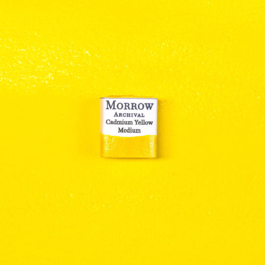 Close-up image of a half pan of Cadmium Yellow Medium handmade watercolor paint, featuring a vivid, golden-yellow hue with a smooth, opaque surface. The pan rests on a neutral background, emphasizing the pigment‚Äôs bold color and artisanal craftsmanship. Ideal for artists seeking a warm, permanent yellow with rich historical and professional pedigree.