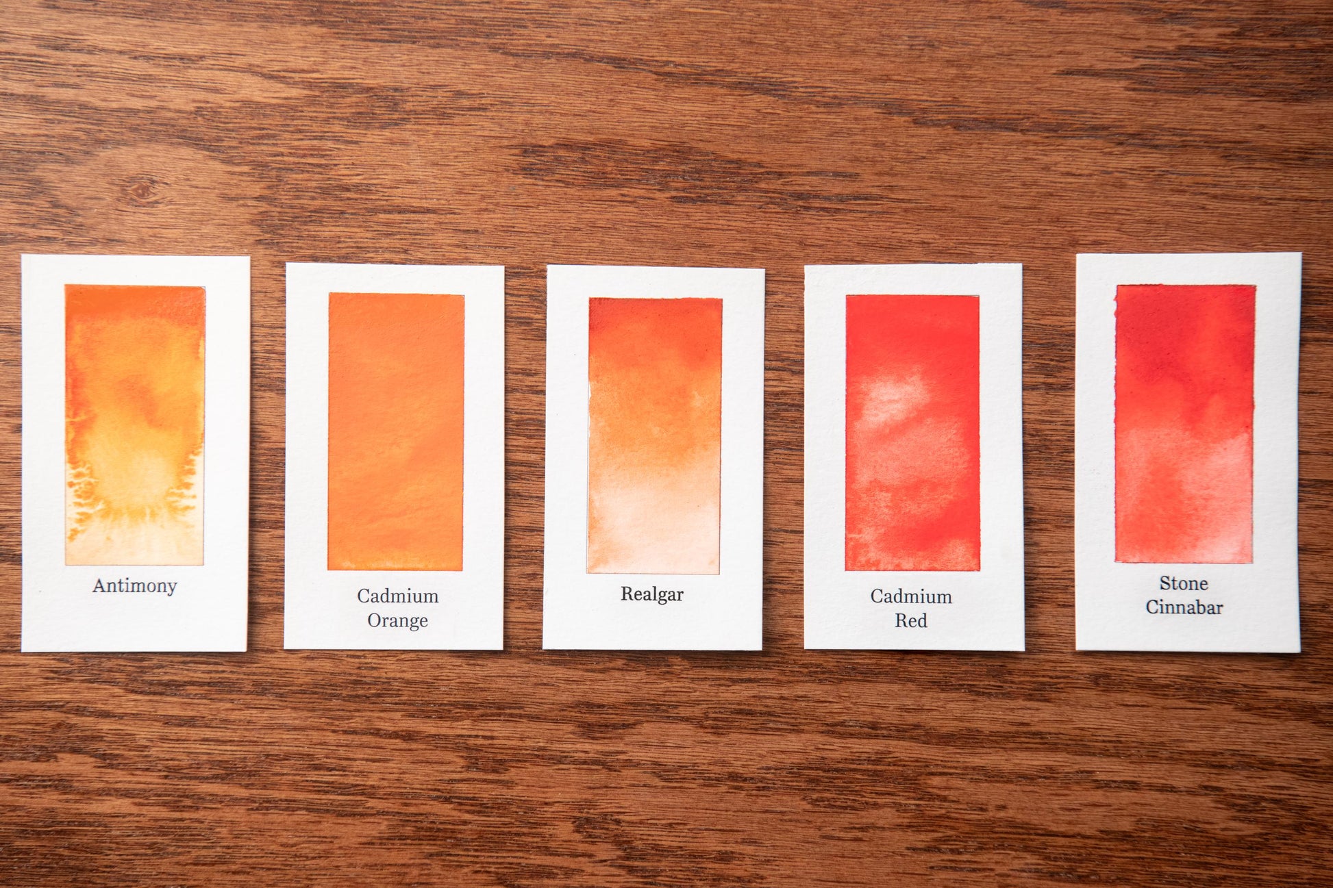 five cards with different shades of red paint, each labeled with a different color name.