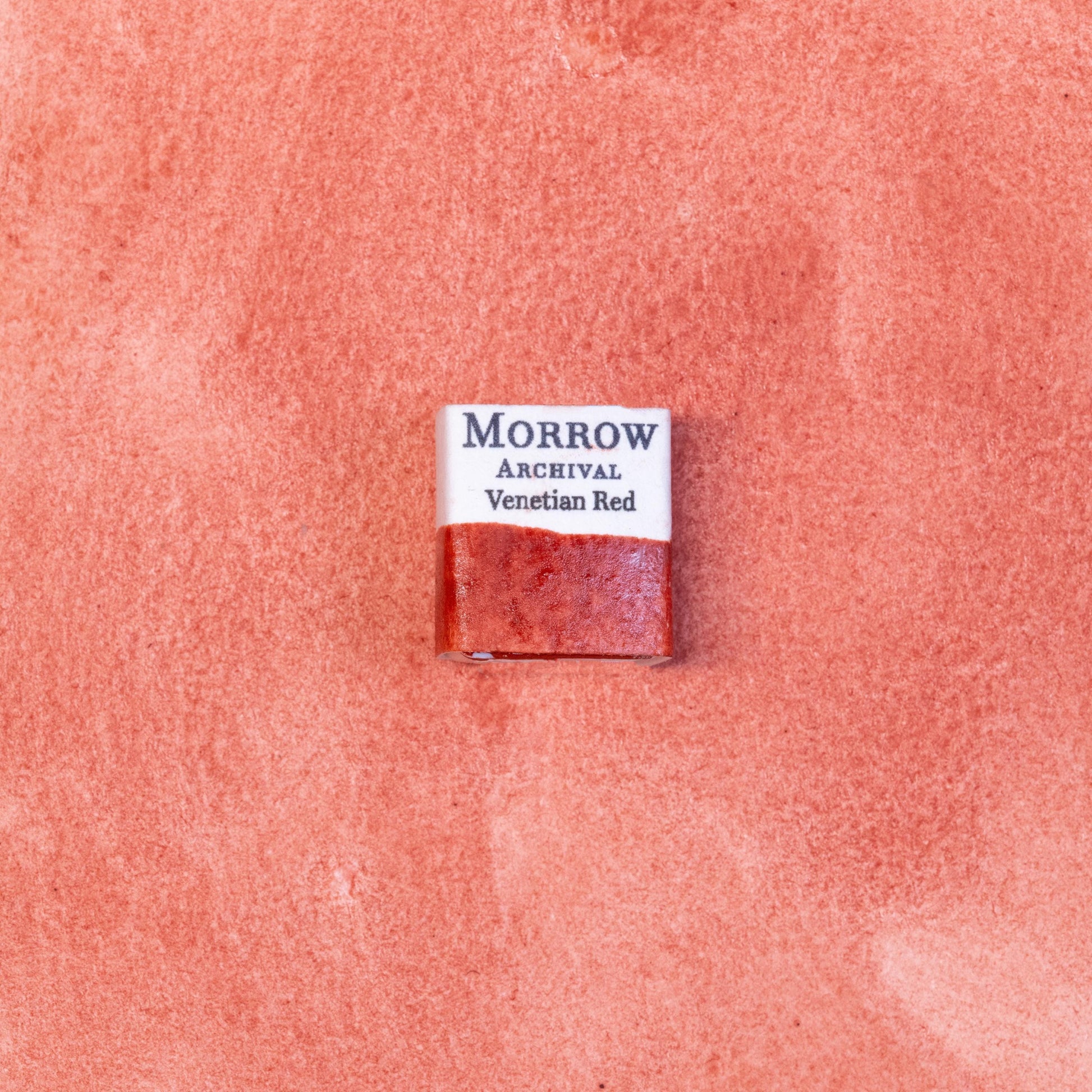 Close-up image of a half pan of Venetian Red handmade watercolor paint, displaying a deep, warm red with earthy undertones and a smooth matte finish. The richly pigmented paint is set against a neutral background, highlighting its natural mineral origin and artisanal craftsmanship. Ideal for artists seeking traditional, non-toxic, earth-based watercolors with historic character.