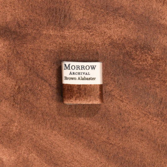 Handmade Brown Alabaster natural watercolor paint half pan resting on a textured watercolor painting. Crafted from pure single-pigment natural stone, this warm, earthy brown offers soft granulation and gentle transparency, ideal for botanical illustration, landscape painting, and historical artwork. A perfect eco-friendly gift for watercolor artists, nature lovers, and collectors seeking small-batch, archival-quality, all-natural handmade pigments inspired by ancient materials.