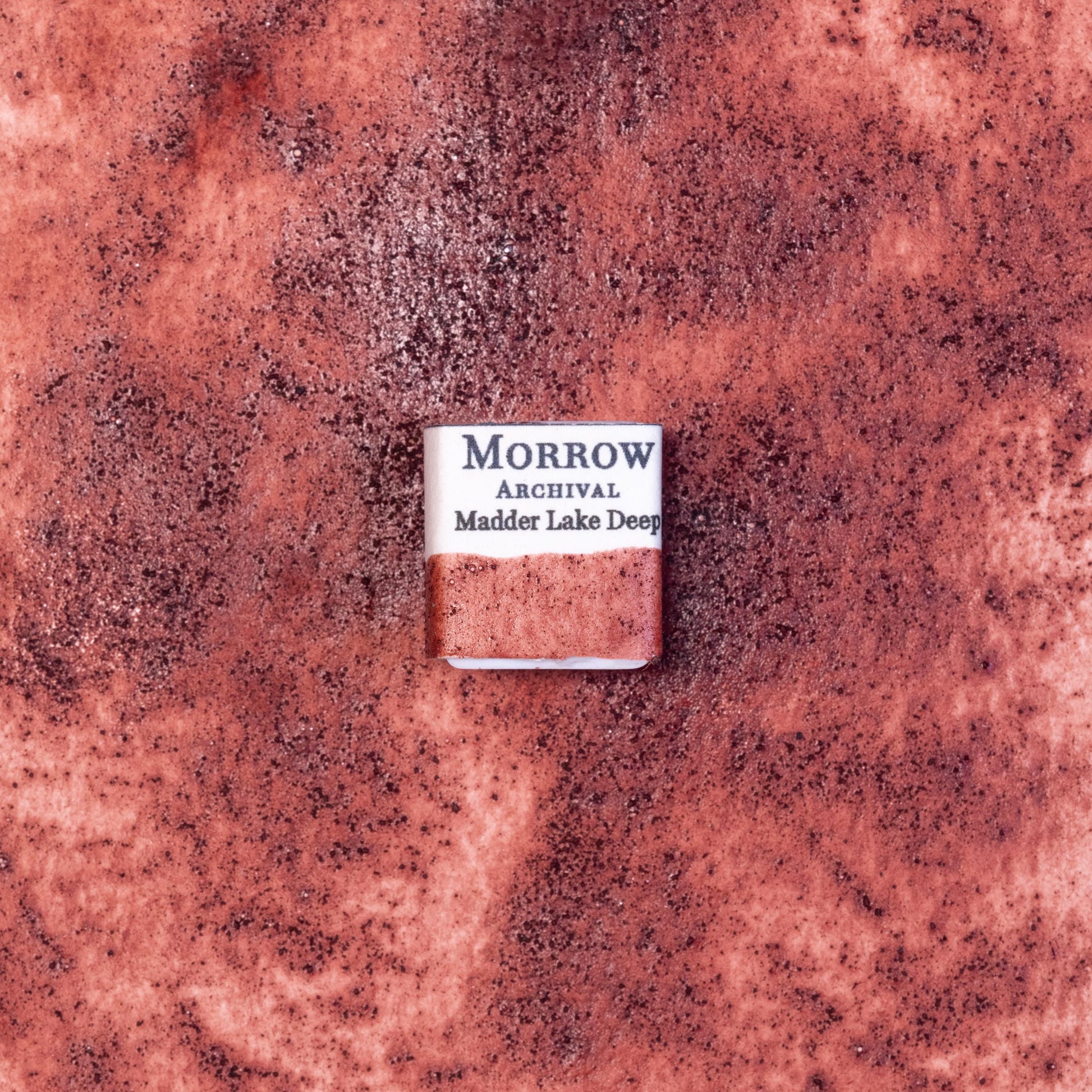 Close-up image of a half pan of Madder Lake Deep handmade watercolor paint, featuring a rich crimson hue with soft violet undertones and a translucent, matte finish. The pan rests on a neutral background, highlighting the pigment‚Äôs botanical origin and artisanal, small-batch craftsmanship. Ideal for artists seeking a historically accurate, plant-based red with elegance and warmth.