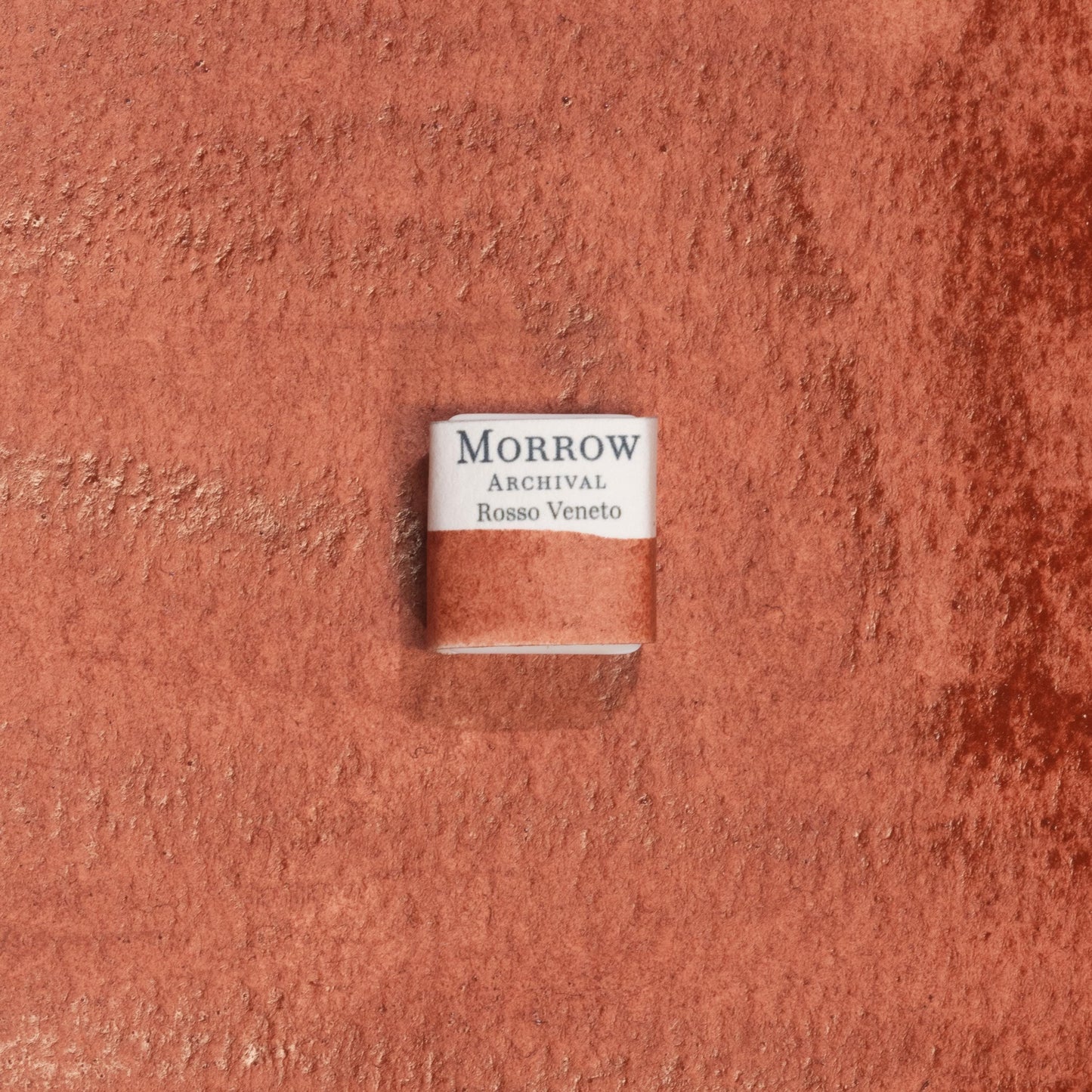 Handmade Rosso Veneto Red Earth natural watercolor paint half pan displayed on a textured watercolor painting. Crafted from pure single-pigment red earth sourced from northern Italy, this warm, deep red offers soft granulation and rich transparency, perfect for classical painting, botanical art, and historical illustration. A timeless eco-friendly gift for watercolor artists and collectors seeking small-batch, archival-quality, all-natural handmade pigments with regional heritage.