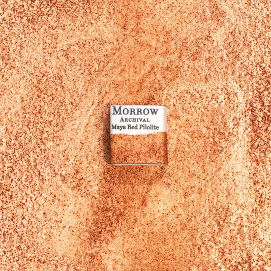 Handmade Maya Red Pilolite natural watercolor paint half pan shown on a textured watercolor painting. Made from pure single-pigment pilolite mineral used by ancient Mesoamerican cultures, this vibrant red offers rich opacity, strong granulation, and historical authenticity‚Äîperfect for fine art, historical illustration, and restoration work. An exceptional eco-friendly gift for watercolor artists and collectors seeking small-batch, archival-quality, all-natural handmade pigments.