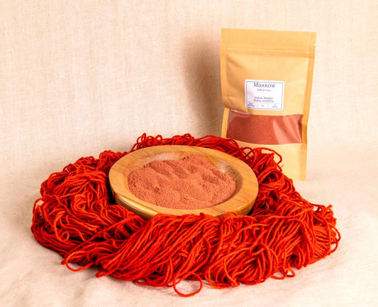 Indian Madder natural dye by Morrow Archival, shown as a rich red powder in a wooden bowl, surrounded by vibrant orange-red wool yarn, with a labeled kraft bag in the background. Made from Rubia cordifolia roots, this historic botanical dye yields deep reds and warm corals used in textiles for centuries. Ideal for natural dyeing, eco-printing, and traditional fiber arts. Hand-processed, small-batch, and sustainably sourced.